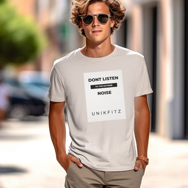 A stylish man in a white T-shirt with bold text that reads 'Don't Listen to the Outside Noise' by Unikfitz, walking confidently down a sunlit urban street. His minimalist active street wear exudes a motivational vibe perfect for modern lifestyles.