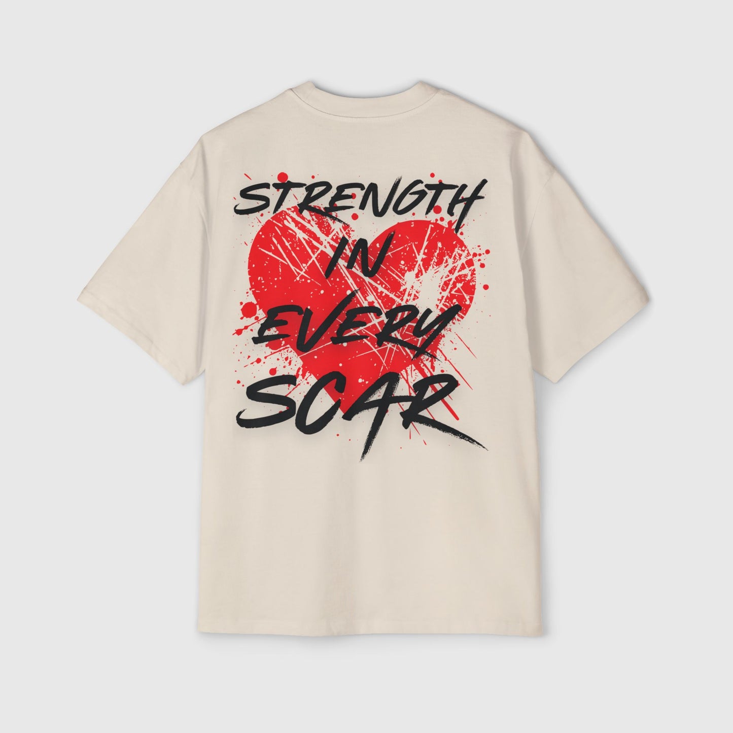 A beige oversized T-shirt laid flat, featuring a large red heart with splatter art and the bold slogan 'Strength in Every Scar' in black graffiti-style text. A powerful piece of active street wear that motivates with its striking and inspirational design.