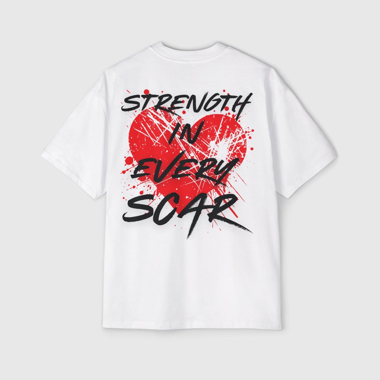 A white oversized T-shirt laid flat, featuring a bold red heart with splattered paint details and the slogan 'Strength in Every Scar' written in edgy black font. A statement piece of active street wear for the fearless misfits, celebrating resilience and self-expression.