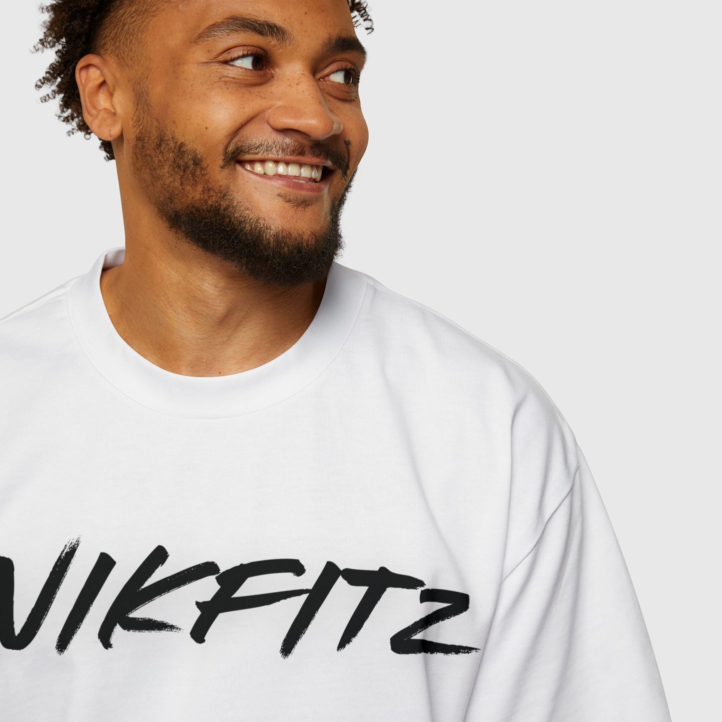 Man smiling confidently in a white UNIKFITZ t-shirt, a perfect blend of men's clothing and streetwear style, ideal for gym or casual wear