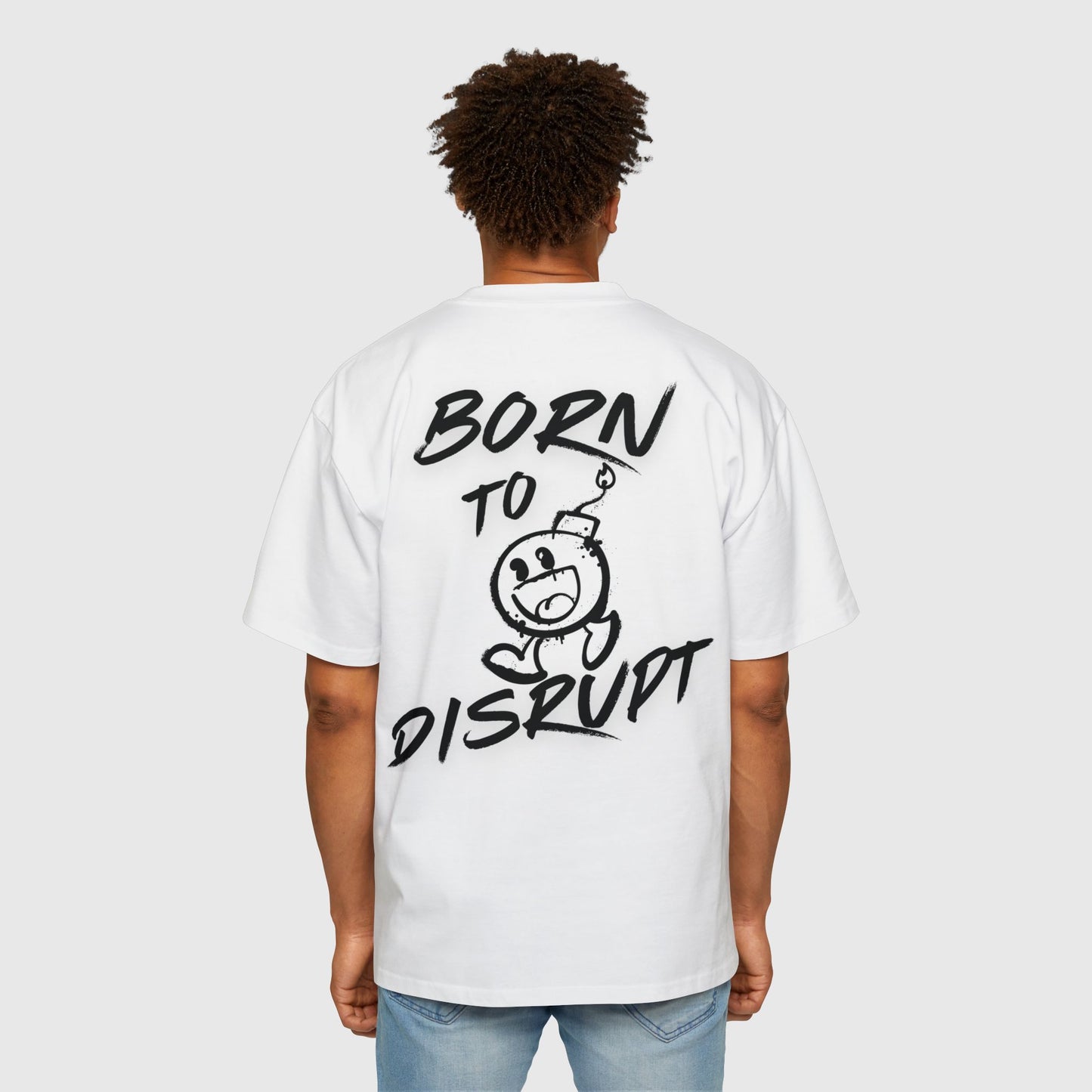 Rear view of a man wearing a white oversized t-shirt with 'Born to Disrupt' graphic, exemplifying bold streetwear in men's clothing essentials