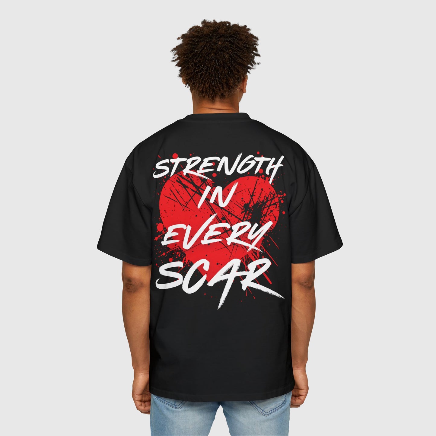 Back view of a black oversized men's t-shirt with striking red heart graphic and 'Strength in Every Scar' lettering. Street wear, essential t-shirt, and stylish t-shirt for men