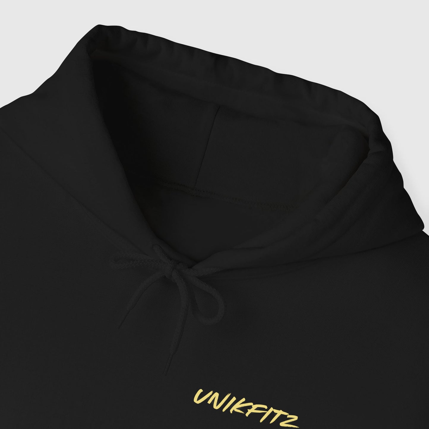 Close-up view of a sleek black men's hoodie showcasing the UNIKFITZ logo in vibrant yellow, emphasizing minimalist streetwear for men’s essential clothing