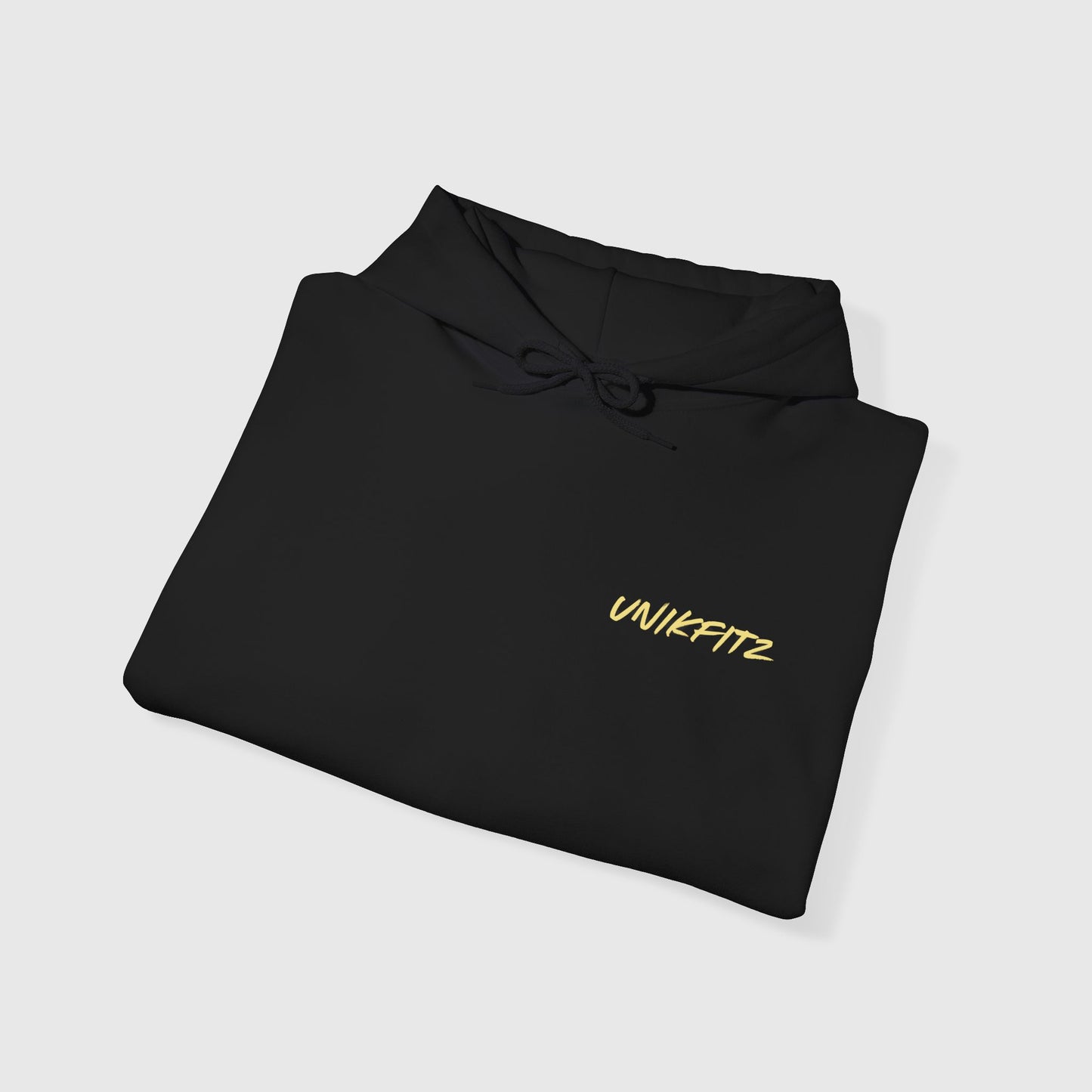 A folded black UNIKFITZ men's hoodie with bold yellow branding, perfect for streetwear enthusiasts and gym-goers seeking an essential hoodie for style and comfort