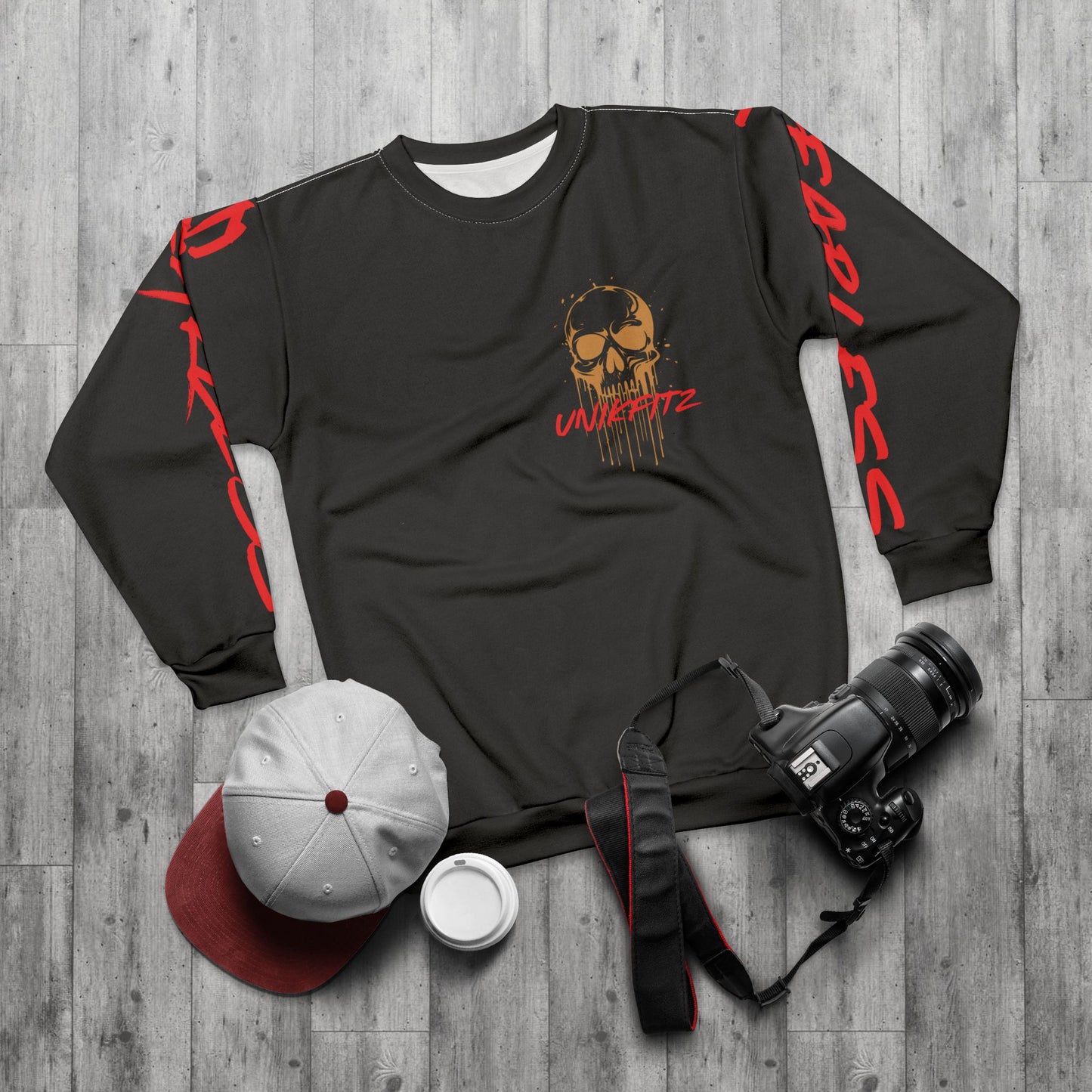 Flat-lay display of an olive green sweatshirt featuring a striking golden skull and 'Unikfitz' text in red, styled with 'Fearless' text on the sleeves. Paired with a gray cap, coffee cup, and DSLR camera, showcasing urban street wear for men. Perfect for men's clothing gym outfits and essential sweatshirts for men