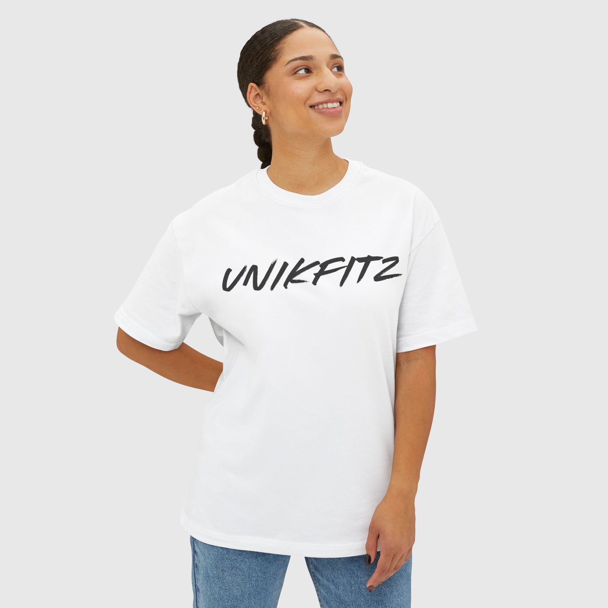 A woman smiling in a white oversized UNIKFITZ T-shirt featuring a striking black logo design. Ideal for essential men's wear and street wear, combining style and comfort effortlessly.