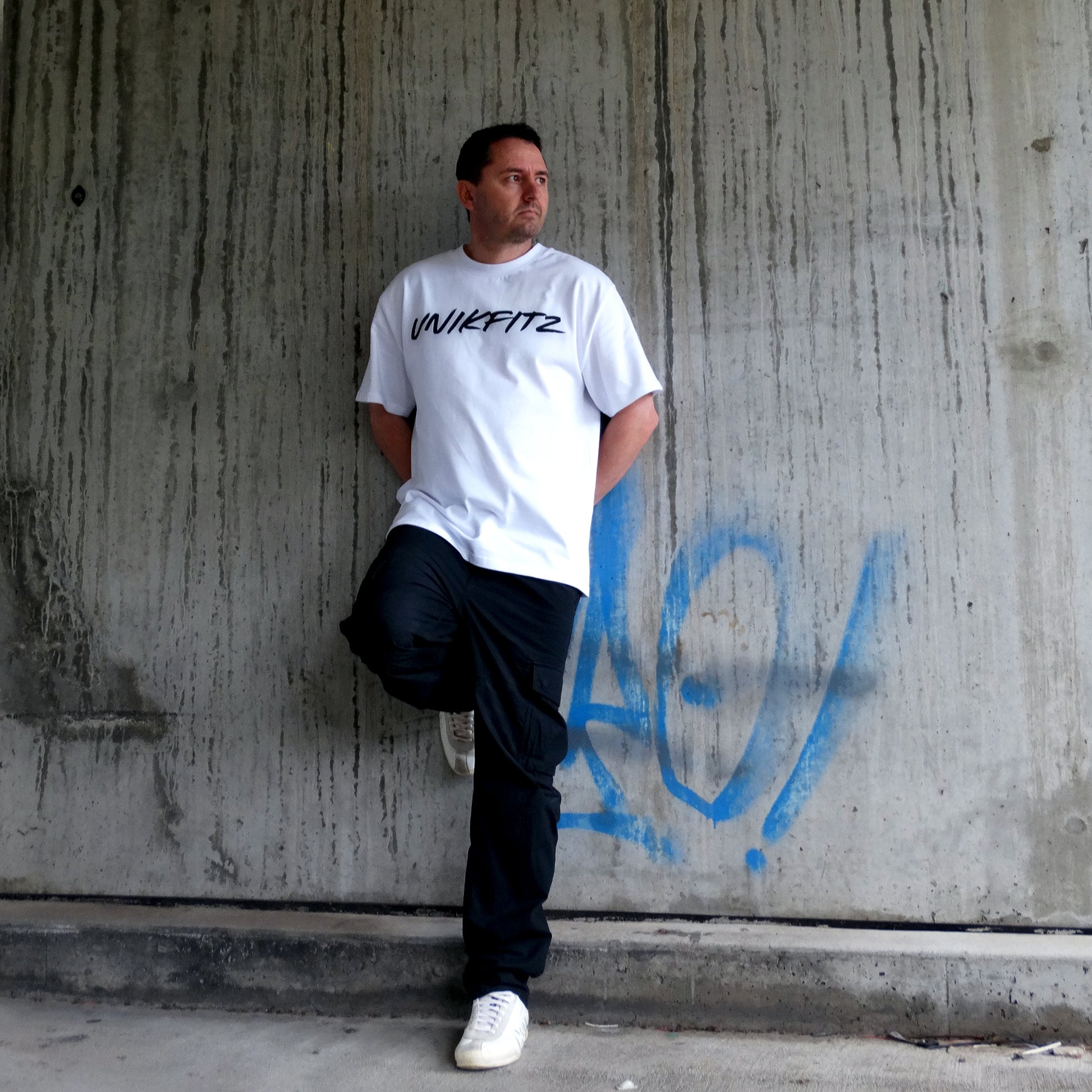 Model wearing the white 'Born to Disrupt' t-shirt by UNIKFITZ, featuring a sleek front logo. This oversized men’s t-shirt essential blends gym-ready durability with streetwear appeal, making it a must-have in any Australian streetwear men’s clothing collection.