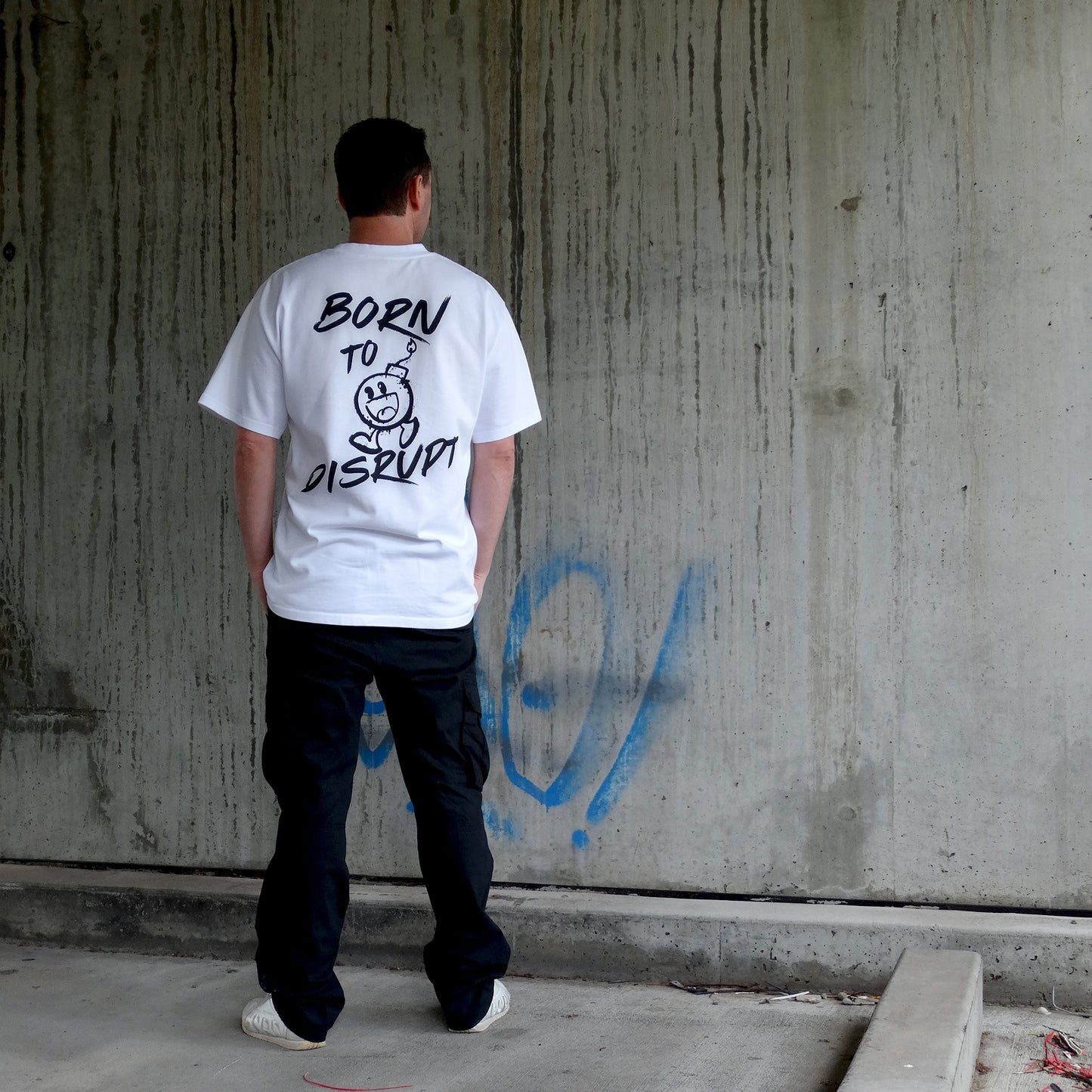 Back view of a model in the 'Born to Disrupt' oversized white t-shirt, showcasing rebellious typography and bold cartoon bomb artwork. Crafted for streetwear enthusiasts, gym lovers, and those who embrace disruption, this men's t-shirt essential is a statement piece in modern Australian streetwear.