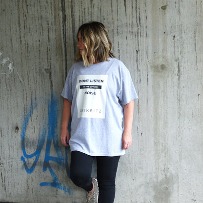 Model wearing the UNIKFITZ "Don't Listen to the Outside Noise" women's t-shirt in sport grey. A bold Australian streetwear essential designed for self-expression and gym wear. The premium cotton tee features a high-contrast front print and a relaxed fit for comfort