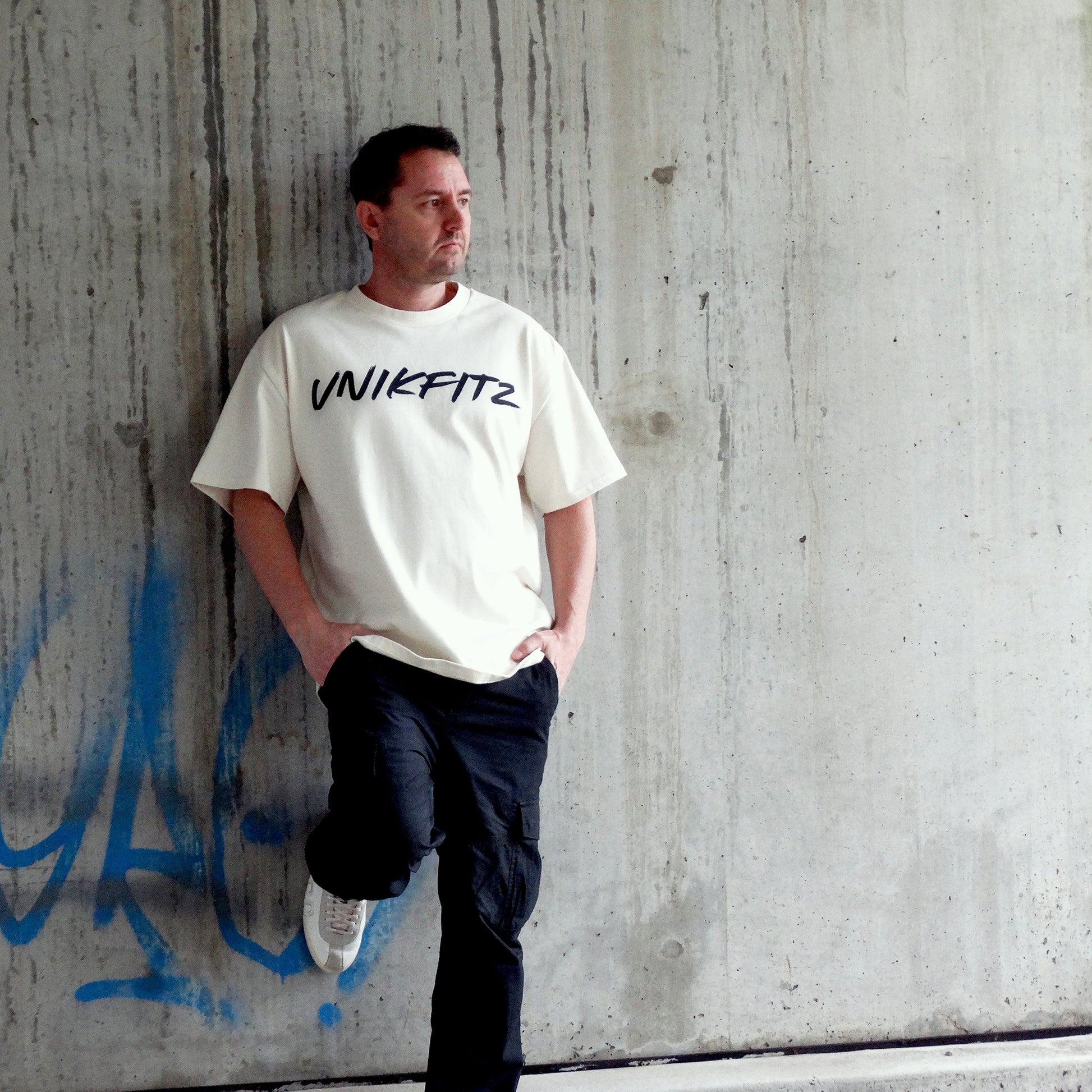Model wearing the 'Live to Inspire' oversized men's t-shirt by UNIKFITZ in an urban streetwear setting. This premium Australian streetwear men's clothing piece features a relaxed fit, making it the perfect essential t-shirt for men who love street wear and gym-ready fashion.