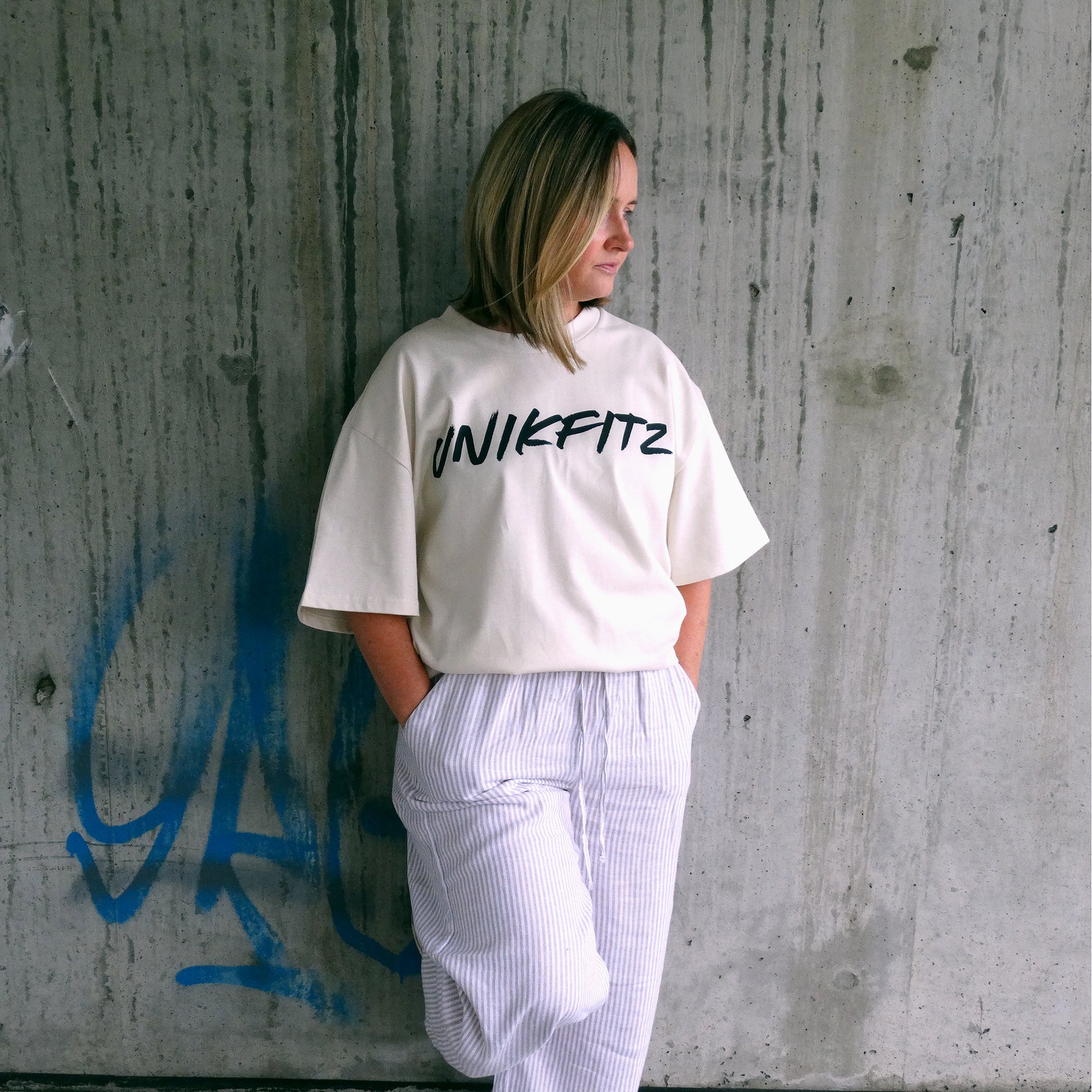 Model wearing the 'Live to Inspire' oversized women's t-shirt by UNIKFITZ in an urban streetwear setting. This premium Australian streetwear women's clothing piece features a relaxed fit, making it the perfect essential t-shirt for women who love street wear and gym-ready fashion.